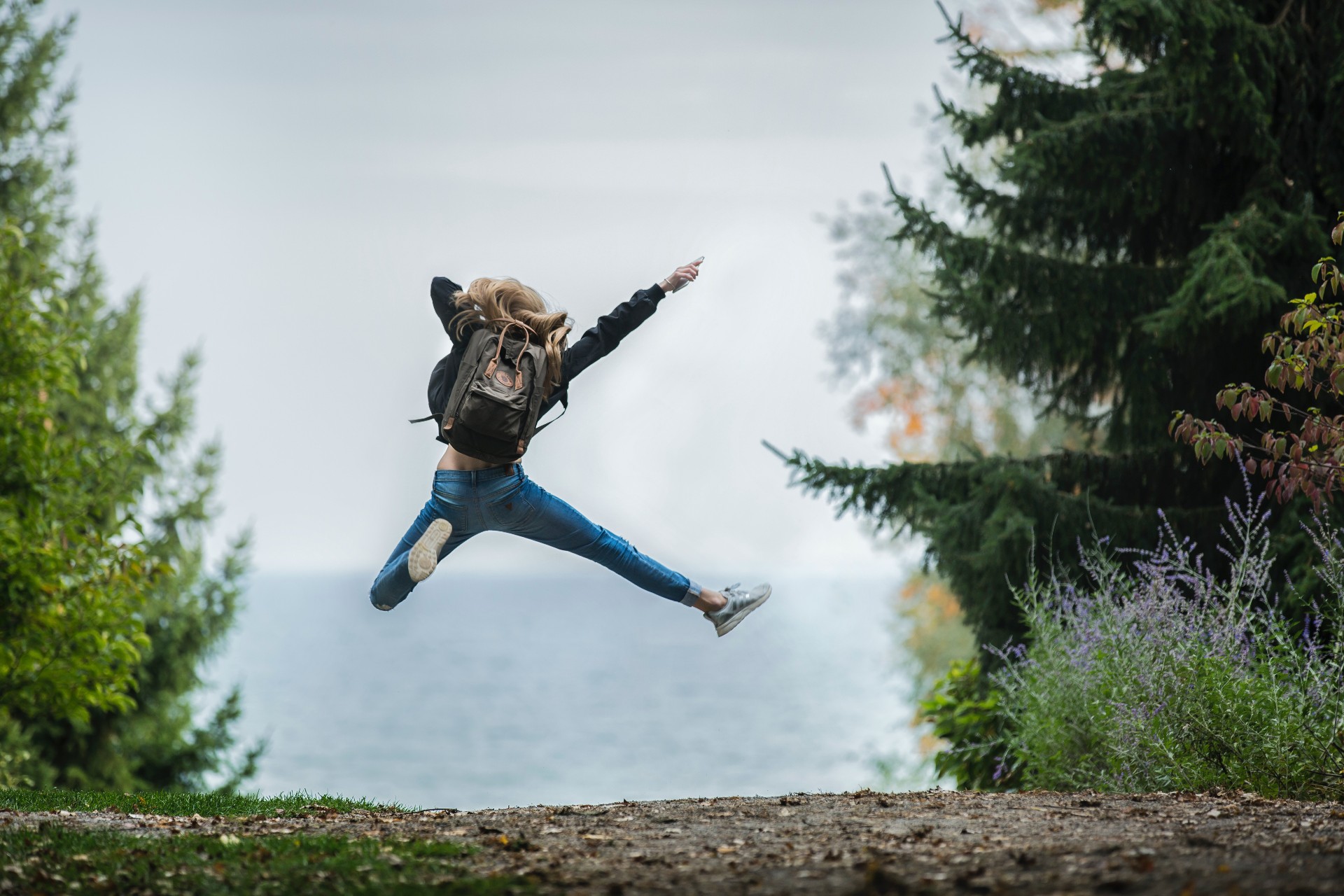 Woman jumping wearing green backpack