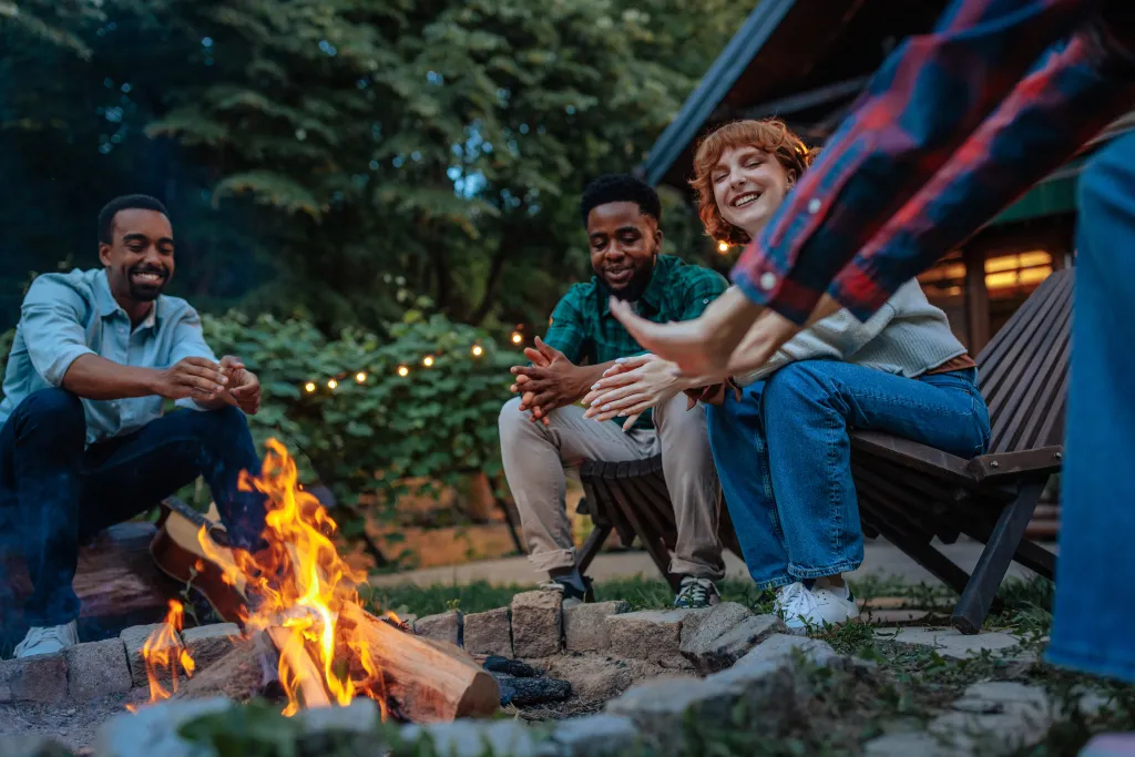 Friends warming up around bonfire in the backyard